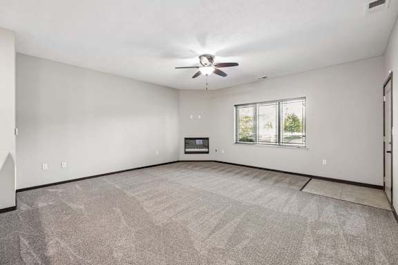 A spacious room with a ceiling fan and a fireplace.