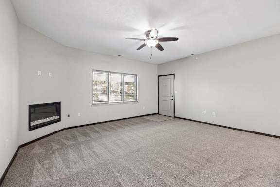 A spacious room with a fireplace and a ceiling fan.
