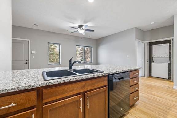 Kitchen breakfast bar with double sink, dishwasher, wood cabinetry, and view into the living area.