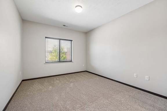 A room with a window and carpeted floor.