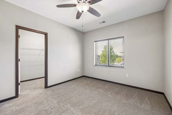 A room with a ceiling fan and a window with blinds.