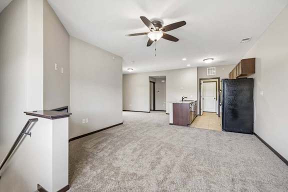 A spacious living room with a ceiling fan and carpeted floor.