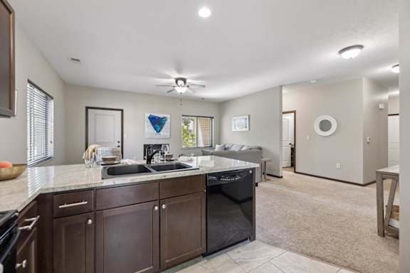 Apartment kitchen with dark wood cabinets, speckled counters, black appliances, tile floor, and windowed door.