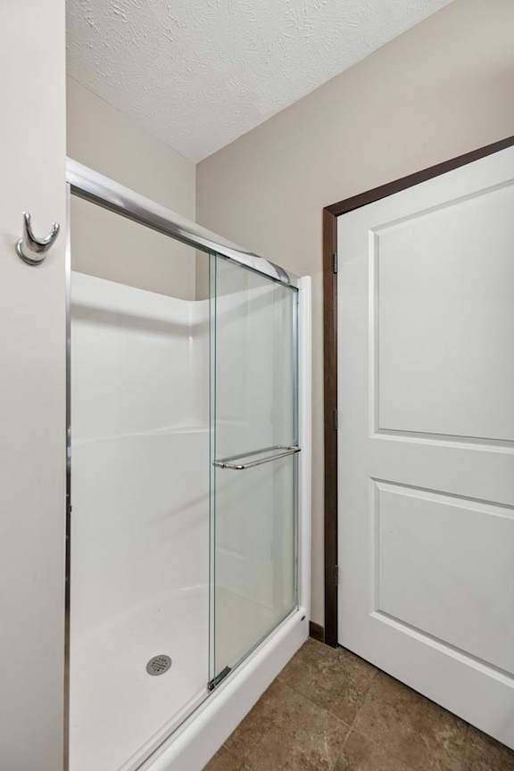 Apartment bathroom shower with sliding glass door, white surround, chrome trim, and neutral walls.