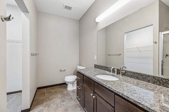 A bathroom with a toilet, sink, and mirror.