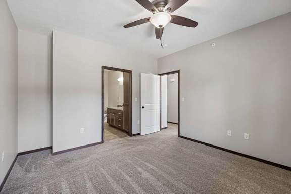 A room with a ceiling fan and carpeted floor.