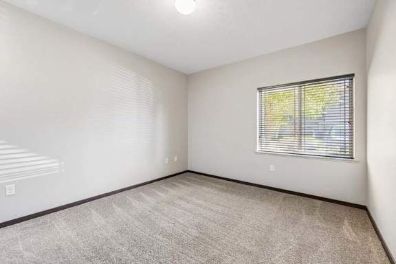 A room with a window and a carpeted floor.