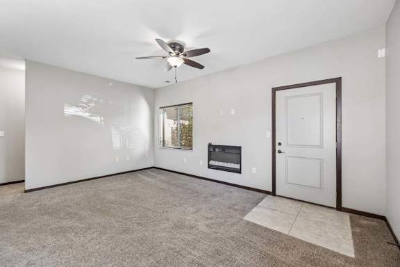 A spacious living room with a fireplace and a ceiling fan.