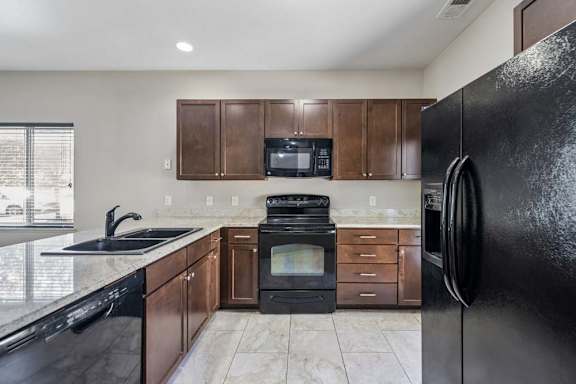 A black refrigerator is on the right side of the kitchen.