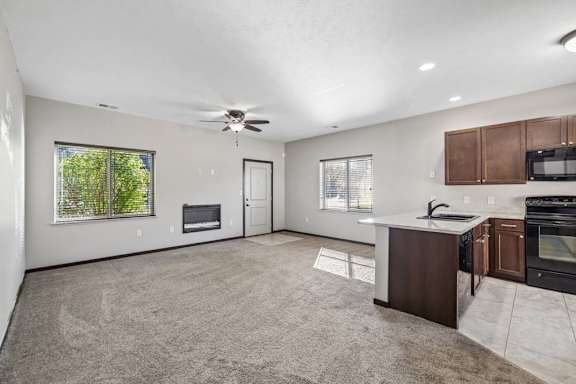 A spacious living room with a fireplace and a kitchen area with brown cabinets.
