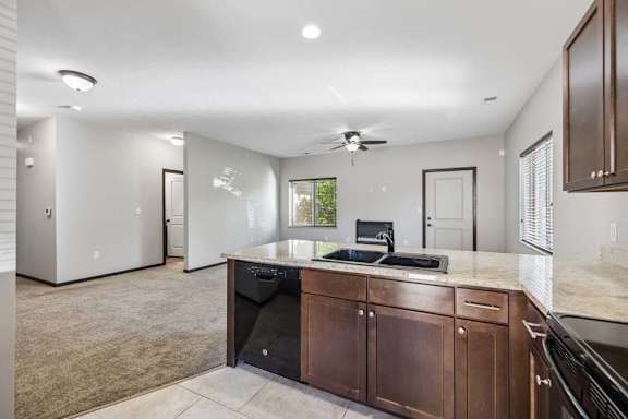 A kitchen with brown cabinets and a black dishwasher.