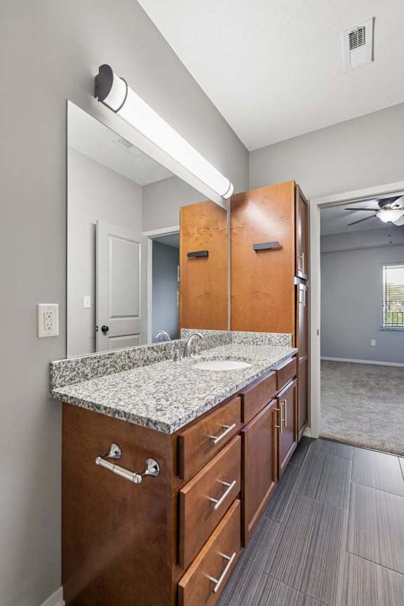 A bathroom with a sink, mirror, and wooden cabinets.