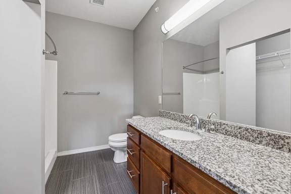 A bathroom with a toilet, sink, and mirror.