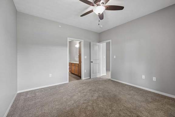 A room with a ceiling fan and carpeted floor.