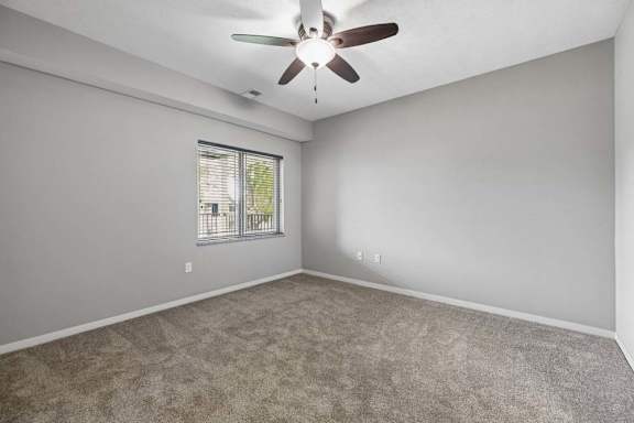 A room with a ceiling fan and a window with blinds.