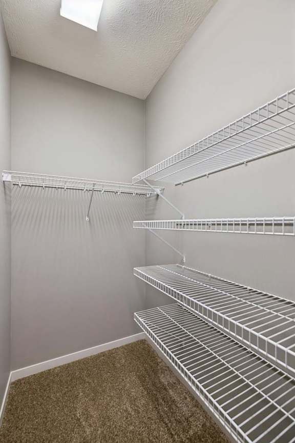 Empty white wire shelves in a walk-in closet.