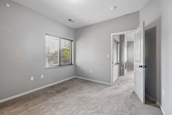 A room with a carpeted floor and a window with blinds.