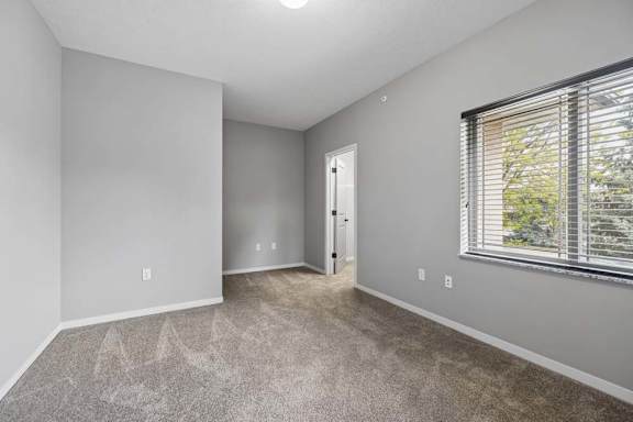 A room with a carpeted floor and a window with blinds.