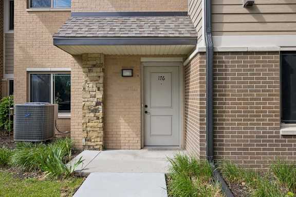 A house with a grey door and a stone pillar in front of it.