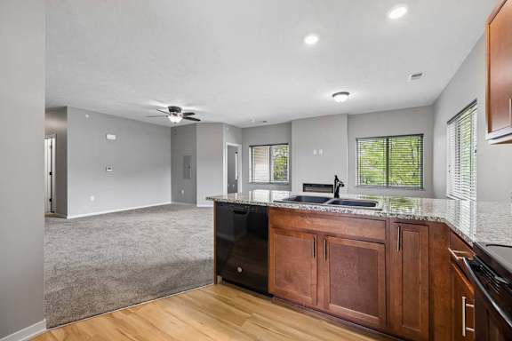 A kitchen with wooden cabinets and a black dishwasher.