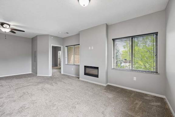 A spacious living room with a fireplace and a ceiling fan.