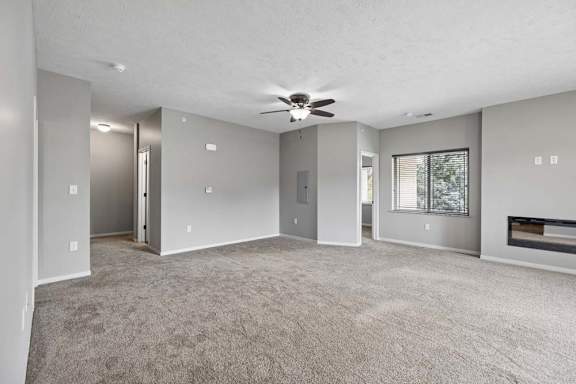 A spacious room with a ceiling fan and carpeted floor.