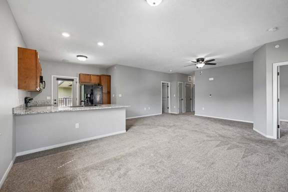 A spacious living room with a kitchenette in the background.