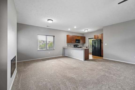 A spacious living room with a kitchen area in the background.