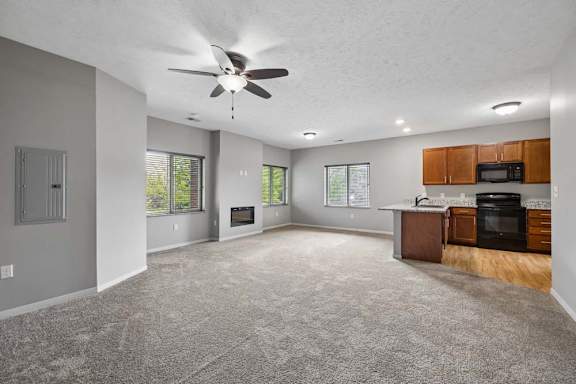 A spacious living room with a ceiling fan and a kitchenette.