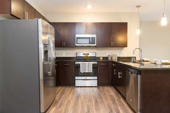 A modern kitchen with dark wood cabinets and stainless steel appliances.