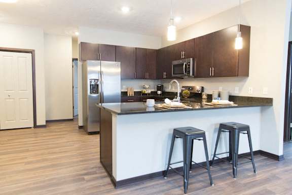 A kitchen with a white counter and black stools.