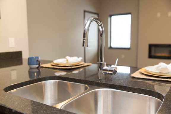 A modern kitchen with a stainless steel sink and faucet.
