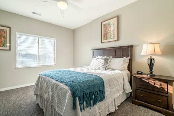 A bedroom with a bed, nightstand, and a ceiling fan.