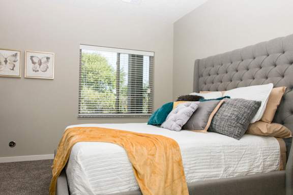 A bedroom with a large bed and a window with blinds.
