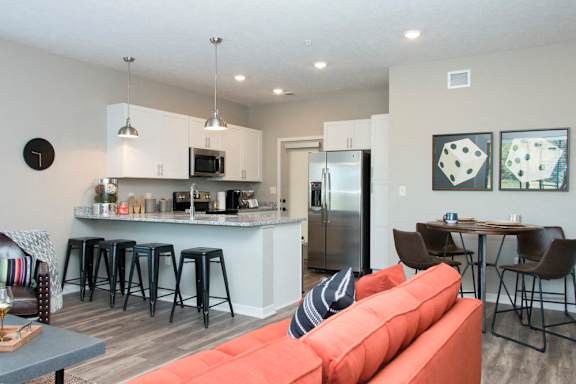 A kitchen with a bar and a dining table with chairs.