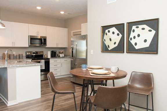 A kitchen with a table and chairs and two paintings on the wall.