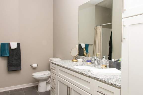 A bathroom with a toilet, sink, and mirror.