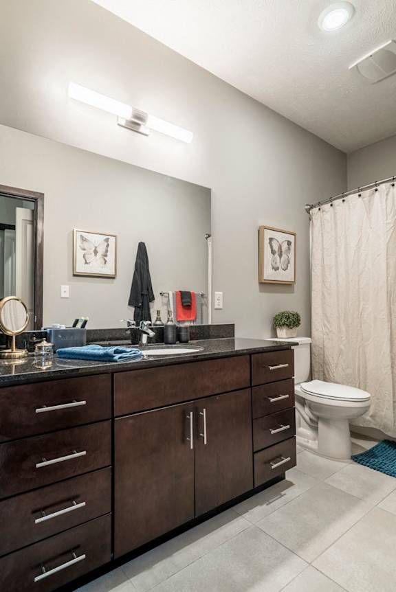Bathroom with dark cabinets and light tile floors at The Villas at Mahoney Park