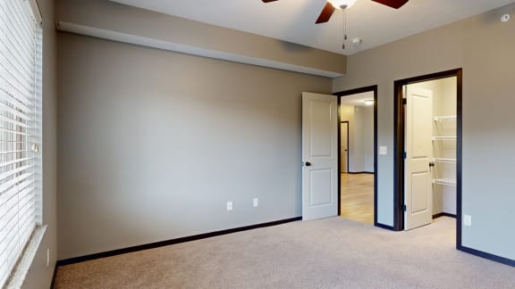 a bedroom with a ceiling fan and a door to walk in closet