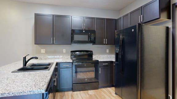 a kitchen with dark cabinets and granite countertops