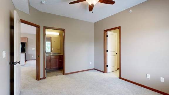 a bedroom with an attached bathroom, ceiling fan, and walk in closet