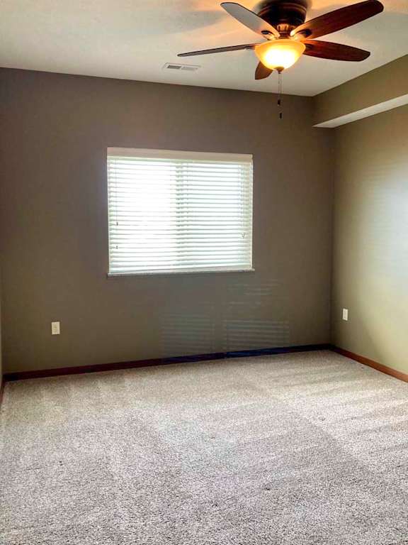 A bedroom with a ceiling fan and a window with blinds.