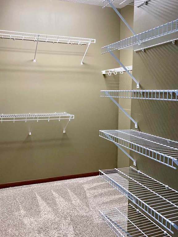 A spacious L-shaped walk-in closet with several wire shelves.