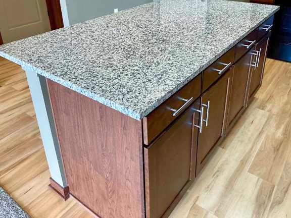 A kitchen island with a granite countertop and wooden cabinets.