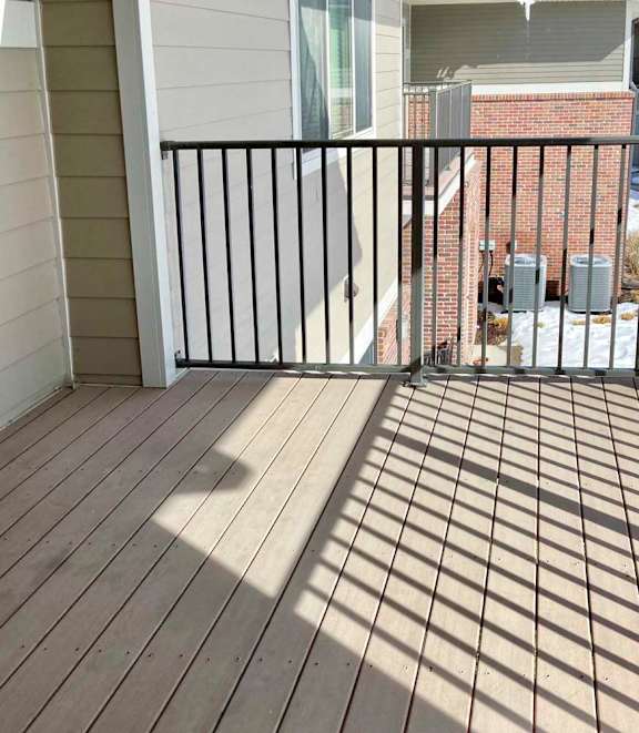 A balcony with a black metal railing and wooden floor.
