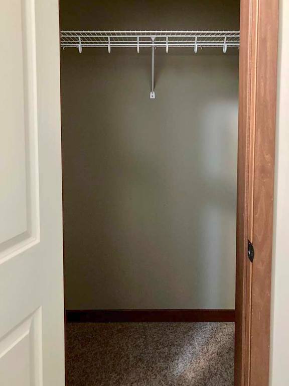 A hall closet with a built-in overhead shelf.