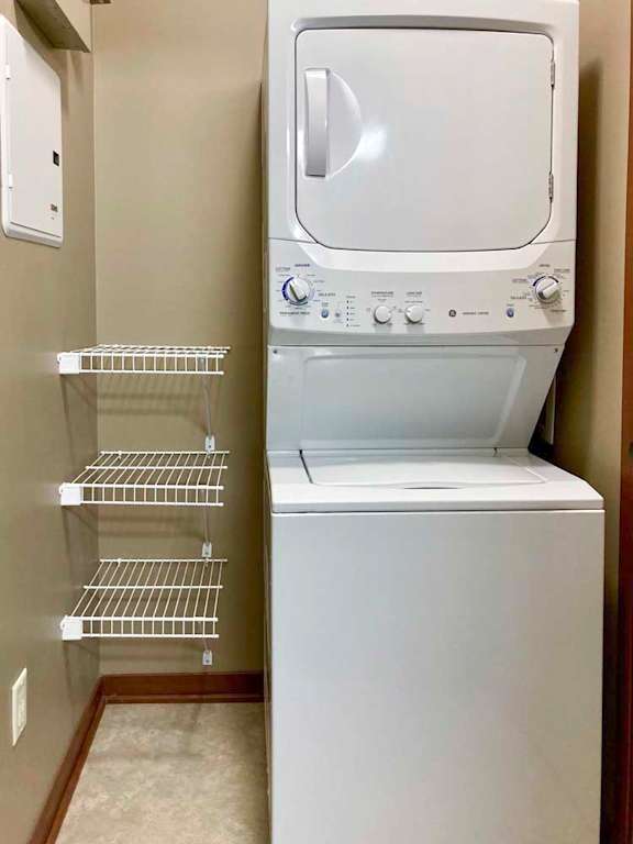 A stacked full-size washer and dryer in a laundry room with built-in shelves.