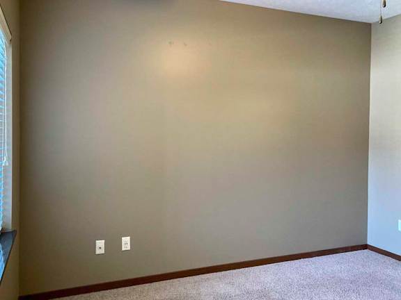 A bedroom with a large window and blinds.