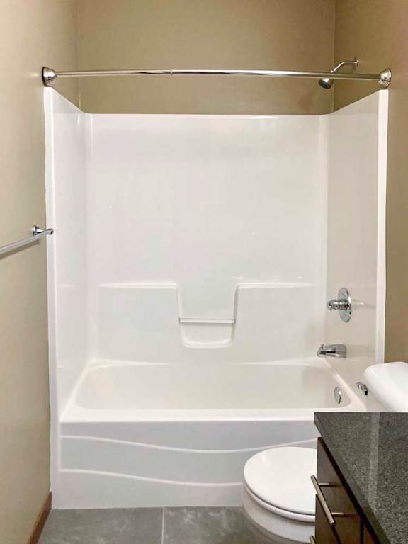 A bathroom with a white tub shower with chrome fixtures.