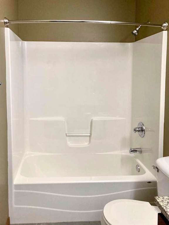 A bathroom with a tub shower with chrome fixtures and a curved curtain rod.